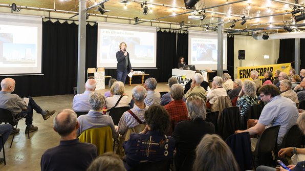 Foto: Armin Simon von .ausgestrahlt steht auf einer Bühne und spricht vor einer Gruppe von Menschen