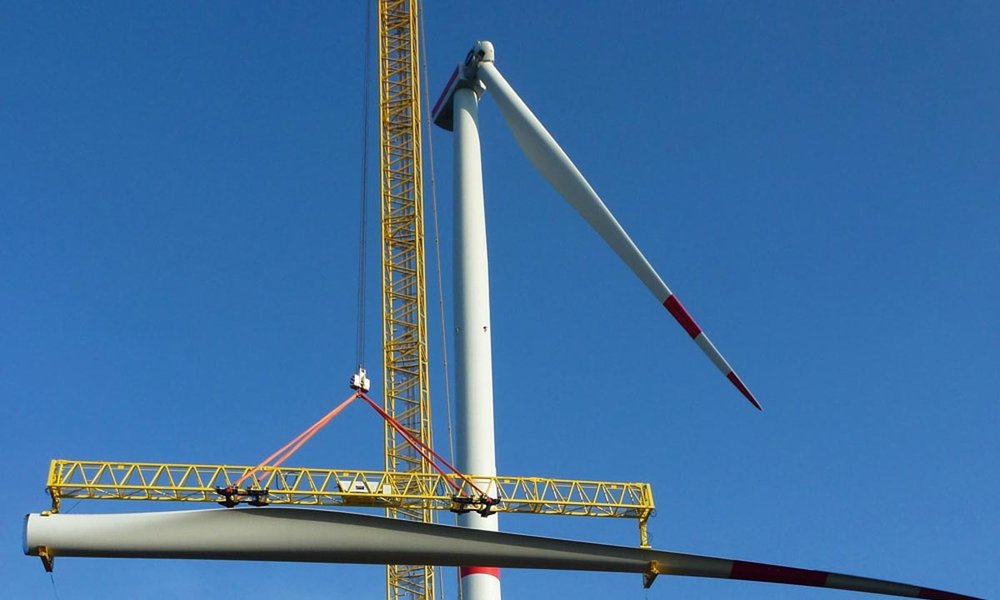 Arbeiten an einem Windrad: ein Kran bewegt einen Flügel
