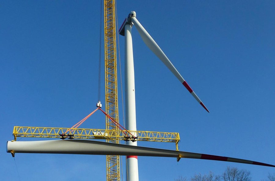 Arbeiten an einem Windrad: ein Kran bewegt einen Flügel