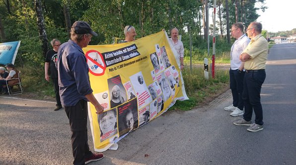 Foto: Drei Männer halten ein Transparent mit der Florderung, die Atomfabrik in Lingen zu schließen.