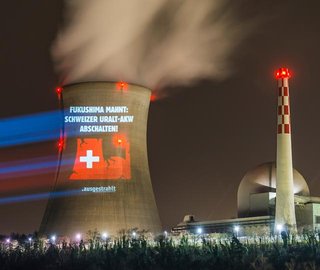 Projektion auf einem AKW-Kühlturm: eine Illustration mit dem Text "Fukushima mahnt - Schweizer AKW abschalten"