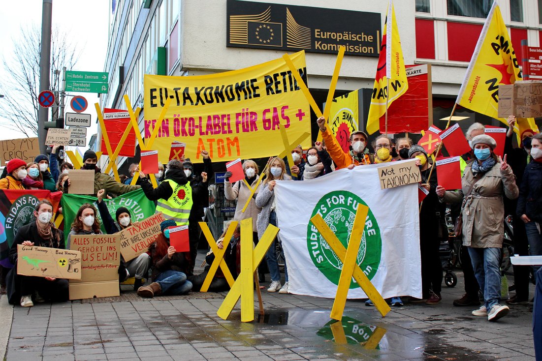 Protestierende Menschengruppe mit gelben X aus Holz, Anti-Atom-Fahnen und einem Banner "EU-Taxonomie retten!"