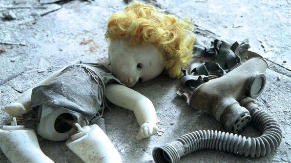 Eine kaputte Puppe liegt auf dem Fussboden neben einer Atemschutzmaske