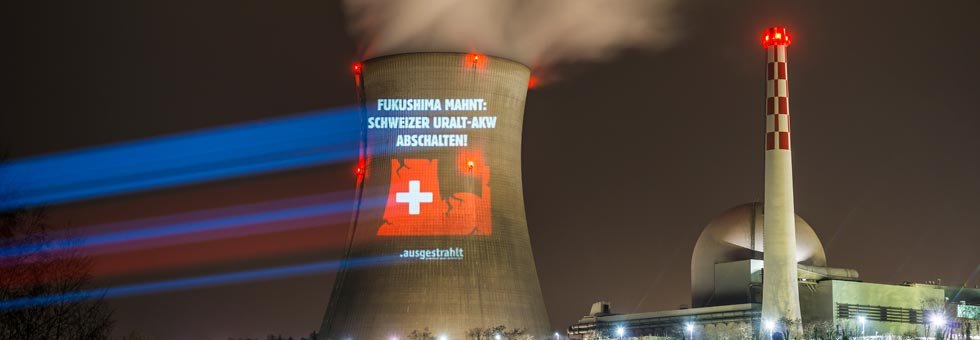 Projektion auf einem AKW-Kühlturm: eine Illustration mit dem Text "Fukushima mahnt - Schweizer AKW abschalten"