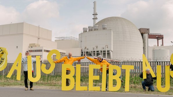 Foto: Atomkraftgegner*innen stehen vor dem AKW Brokdorf und halten große gelbe Buchstaben, die den Satz "aus bleibt aus" ergeben.