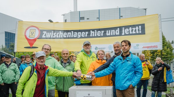 Foto: Atomkraftgegner*innen stehen vor Forschungsreaktor in Garching und simulieren eine Grundsteinlegung für ein Zwischenlager vor Ort